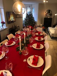 a dining room table set for christmas with red napkins and place settings on it