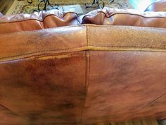 a brown leather couch sitting on top of a hard wood floor