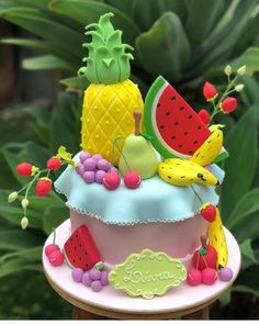 the cake is decorated with fruit and has pineapples, watermelon, bananas, cherries, strawberries