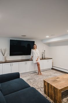 a woman is standing in the living room with her feet on the counter and looking at the camera