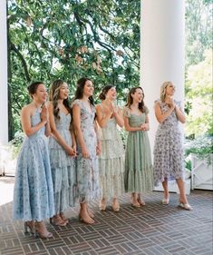 a group of women standing next to each other on top of a brick floor covered porch