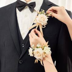 a man in a tuxedo adjusts his boutonniere with flowers