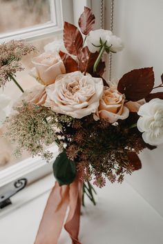 a bouquet of flowers sitting on top of a table next to a window sill