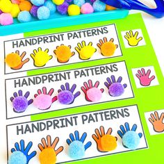 colorful handprint patterns on a green board with pom - poms and scissors