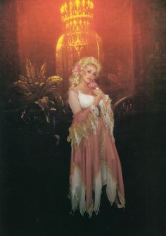 a woman standing in front of a chandelier wearing a pink and white dress