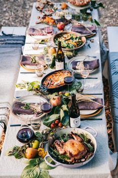 a long table is set up with food and wine for an outdoor dinner or party