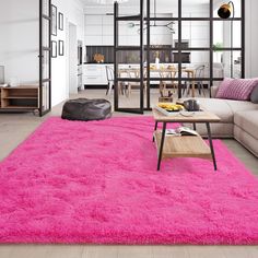 a living room filled with furniture and a pink rug