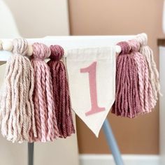 a pink and white number one banner with tassels hanging from it's sides