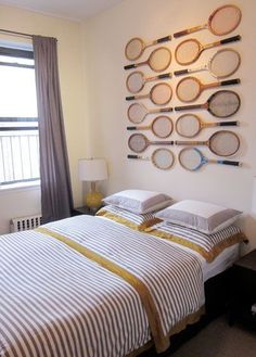 two beds with tennis rackets mounted to the wall above them in a bedroom area