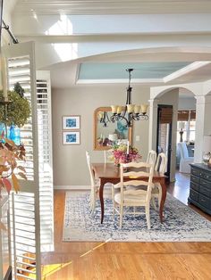 a dining room table and chairs in a living room with hardwood floors, white walls and blue accents