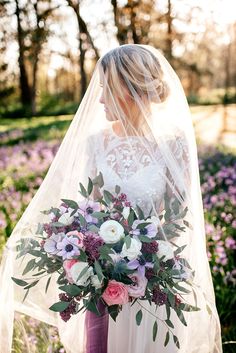 a woman in a wedding dress holding a bridal bouquet and veil over her head