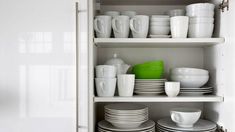 white dishes and cups are stacked on the shelves