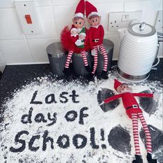 two elfs sitting on top of a pile of snow next to a sign that says last day of school