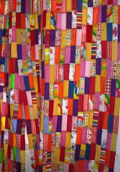 a colorful quilt hanging on the side of a wall