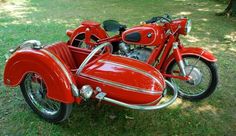 a red motorcycle parked on top of a lush green field