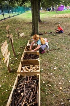 two children are playing in the park with wooden boxes filled with rocks and twigs,