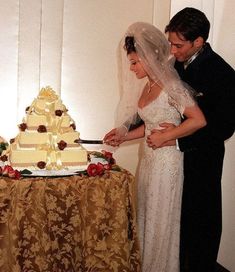 a bride and groom are cutting their wedding cake at the reception table with an elegant cloth draped over them