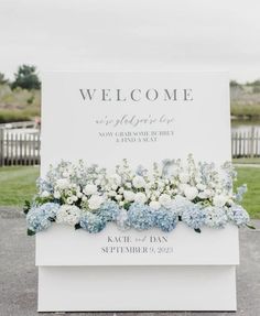 a welcome sign with blue and white flowers