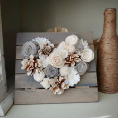 a wooden box with flowers on it next to a vase