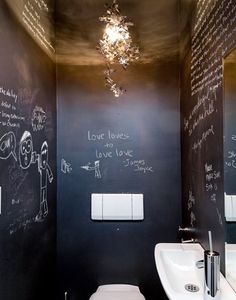 a bathroom with chalk writing on the walls and a toilet in the corner, next to a sink