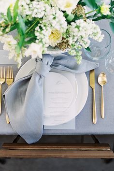 a table setting with silverware and white flowers