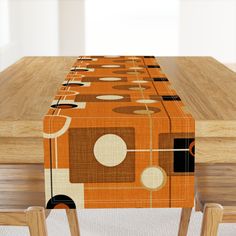 an orange table cloth with circles and dots on it, sitting at a wooden table