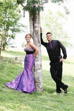 a man and woman standing next to a tree