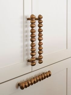 an old door handle is hanging on the side of a white cabinet with wooden knobs