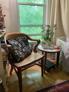 a wooden chair sitting next to a table with a pillow on it's back