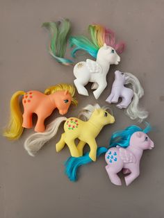 small plastic toy horses are lined up in a row on the floor with long hair