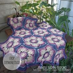 a crocheted blanket sitting on top of a wooden bench next to potted plants