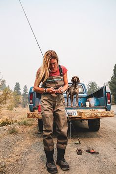 a woman standing in the back of a pick up truck with a dog on it