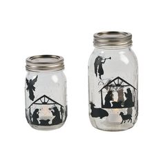 two mason jars with nativity scene painted on the lids, one is clear and the other has silver rims