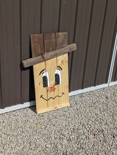 a wooden birdhouse with a face painted on it's side by a wall