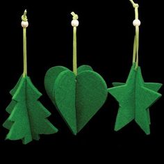 three felt christmas tree ornaments hanging from hooks on a black background, with one green heart and the other two white stars