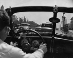 a black and white photo of a woman driving a car