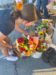 a woman kneeling down with flowers in her hands