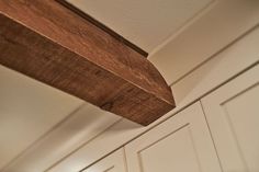 a close up of a wooden shelf in a room with white walls and cupboards