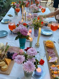 a long table is set with flowers, crackers and cheeses for a party