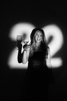 a woman holding a wine glass in front of the number two projected on a wall