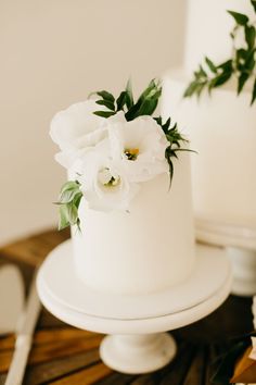 a close up of a white cake with flowers on the top and side, sitting on a wooden table