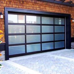 a black garage door is open on a brick building with flowers in the foreground