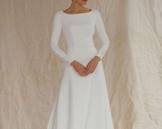 a woman in a white wedding dress with long sleeves