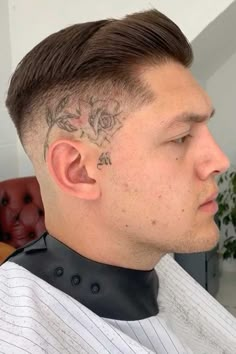 a man with a tattoo on his head sitting in a chair