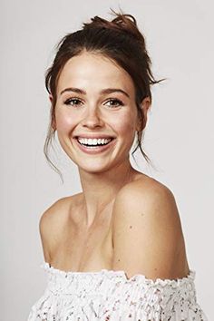 a woman smiling and wearing a white off the shoulder top