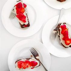 three white plates topped with slices of cake covered in strawberries and chocolate frosting