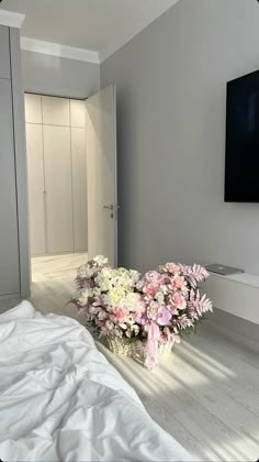 a vase with flowers sitting on the floor in front of a flat screen tv