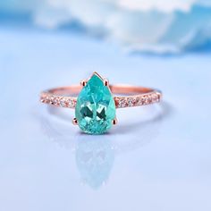 an oval cut aqua blue topazte ring with diamond shoulders on a white background