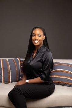 a woman sitting on top of a couch next to pillows