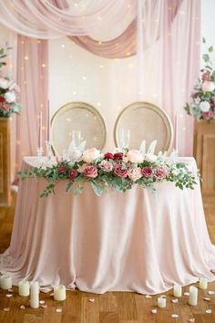 the table is set with two chairs and flowers in front of it, along with candles